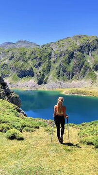 rear view of a woman hiking in the mountains near a scenic alpine lake, Somiedo lake in Spain