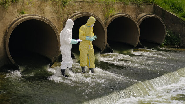 Environmental Researchers Team Walking by Polluted River Drainage