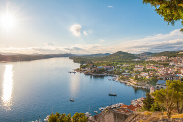 Fototapeta premium View from Saint Michael’s Fortress in Šibenik, Croatia, at sunset, overlooking charming stone houses, the sparkling Adriatic Sea, and a breathtaking coastal panorama bathed in warm golden light.