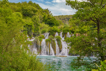 Krka National Park, Croatia, view of the Krka waterfall on a sunny day, featuring cascading water, lush greenery, wooden walkways, and a stunning natural landscape in bright Mediterranean light. © johnkruger1