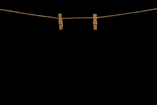 Wooden clothespin on a rope isolated on a black JPEG background. Realistic hanging clip with clothesline for mockups, decorations, and creative designs.