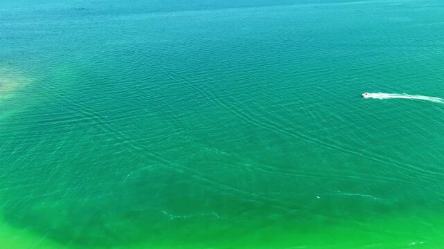 Fast-moving vessel cuts through calm sea, creating frothy trail