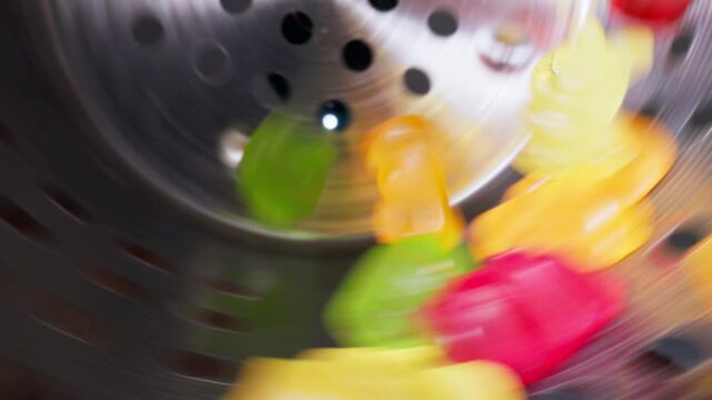 Slow motion Colorful gummy bears marmalade sweets on industrial conveyor. Food production with macro probe lens.