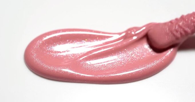 Macro shot of pink liquid lipstick applicator touching a white surface, professional cosmetic product texture and makeup application.