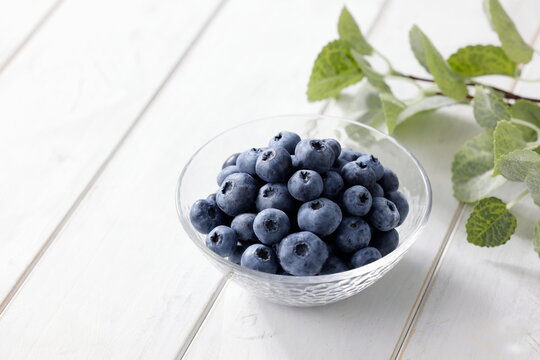 白い木目テーブルに置かれたボウルに入ったブルーベリー　Blueberries in a bowl on a white wooden table