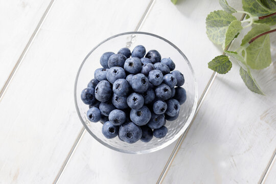 白い木目テーブルに置かれたボウルに入ったブルーベリー　Blueberries in a bowl on a white wooden table