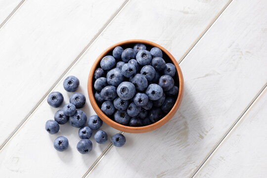 白い木目テーブルに置かれたボウルに入ったブルーベリー　Blueberries in a bowl on a white wooden table