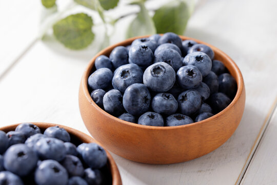 白い木目テーブルに置かれたボウルに入ったブルーベリー　Blueberries in a bowl on a white wooden table