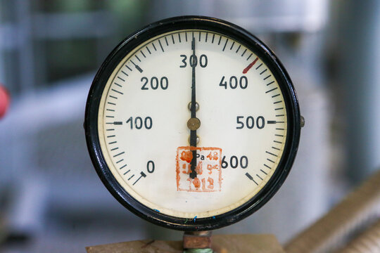 Close-up view of an industrial analog gauge with a black frame and white dial, displaying measurements on a scale from zero to six hundred. The needle indicates current readings on the measuring equip
