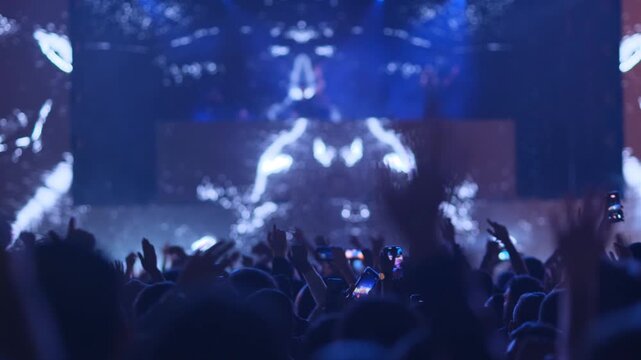 Large crowd dances outdoors at a music festival with lighting effects and flames Music fans express emotions freely, enjoying dance music, entertainment, freedom of expression and a festive atmosphere