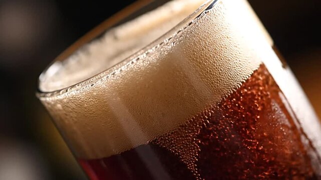 Close-up of dark beer in a glass with a frothy, bubbly head