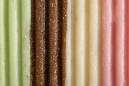Close-up full frame macro view of colorful traditional Indonesian cassava cake texture, gethuk lindri, featuring green, brown, cream, and pink striped patterns.