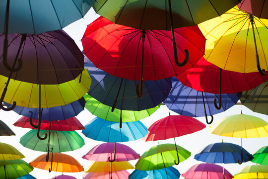 Rows of colorful umbrellas suspended above an outdoor space, vibrant decorative display, creative background, summer festival.