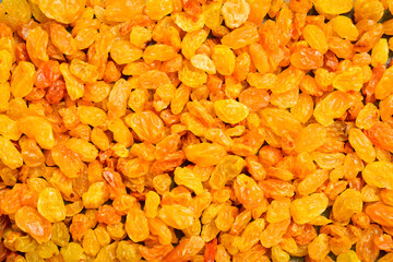 Obraz premium Bright golden dried raisins fill the entire frame creating a textured background. Delicious sweet fruits are rich in vitamins. Perfect picture for healthy eating concepts.