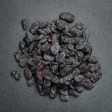 Dark dried raisins fill the entire frame creating a textured background. Delicious sweet fruits are rich in vitamins. Perfect picture for healthy eating concepts.