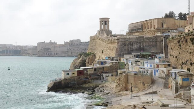 siege bell war memorial rotunda crowns valletta bastion above il fossa cove colorful fishermen boathouses cliffside overcast mediterranean skyline siege bell memorial malta war memorial