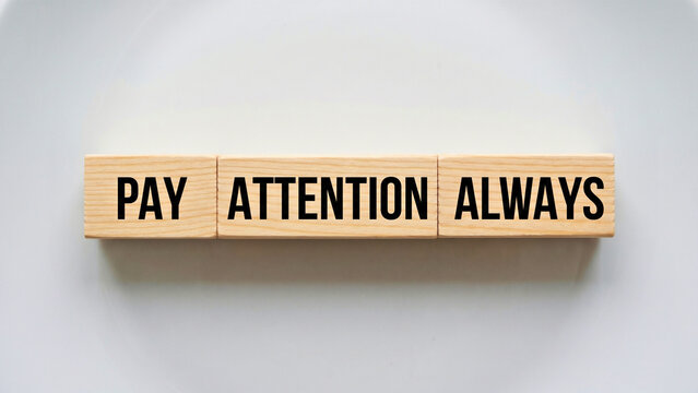 Wooden blocks spelling Pay Attention Always on white ceramic surface overhead wide, attention and awareness concept