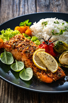 Baked salmon with white rice and Brussels sprouts on wooden table
