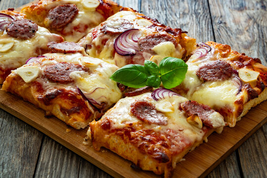 Pizza with sausage, mozzarella cheese, tomato sauce, red onion and broccoli yogurt on wooden table
