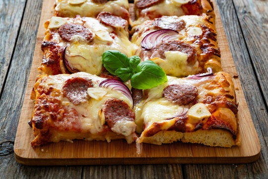 Pizza with sausage, mozzarella cheese, tomato sauce, red onion and broccoli yogurt on wooden table
