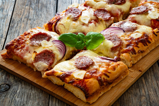 Pizza with sausage, mozzarella cheese, tomato sauce, red onion and broccoli yogurt on wooden table
