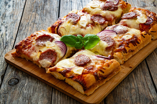 Pizza with sausage, mozzarella cheese, tomato sauce, red onion and broccoli yogurt on wooden table
