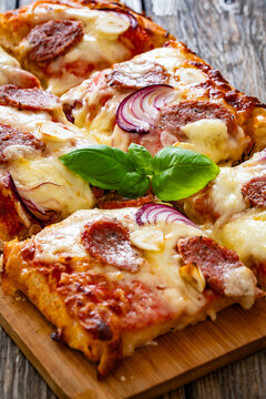 Pizza with sausage, mozzarella cheese, tomato sauce, red onion and broccoli yogurt on wooden table
