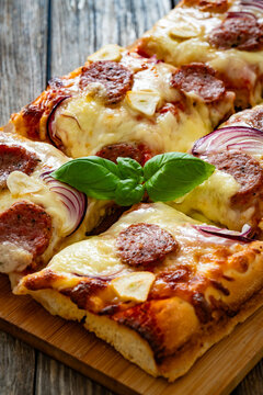 Pizza with sausage, mozzarella cheese, tomato sauce, red onion and broccoli yogurt on wooden table
