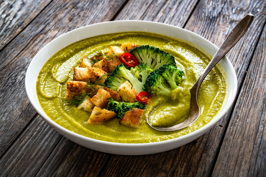 Garnished cream broccoli soup on wooden table
