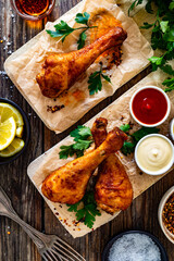 Fototapeta premium Air fryer chicken drumsticks with mayonnaise, ketchup and mustard on wooden table. Top view