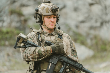 Fototapeta premium Outdoor military concept. Soldier soldier man focus determined brave military combat rifle helmet communication gear