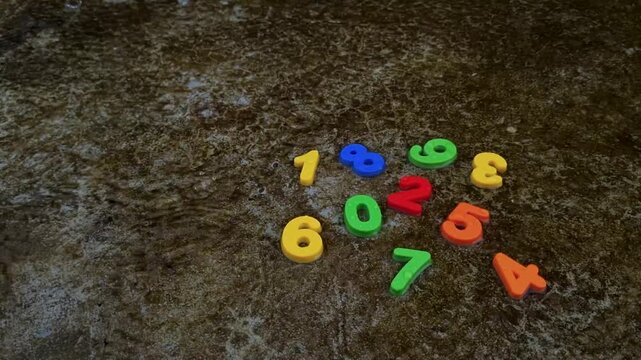 Arrangement of colorful plastic numbers scattered on textured ground number math mathematics