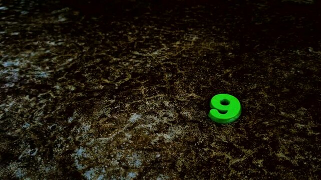 Bright green number nine figure on dark weathered ground digit concrete texture surface aged