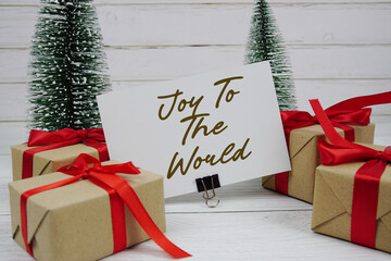 Fototapeta premium Joy to the World text written on paper card with gift box and christmas tree