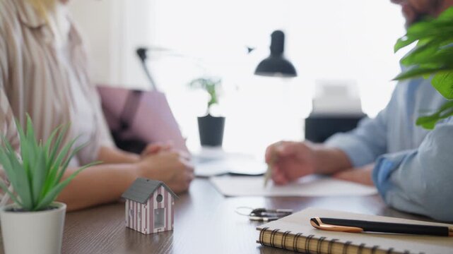 Real estate agent discussing a rental agreement with a client and explaining contract terms in a modern office. Property rental, housing search, lease negotiation and real estate services concept