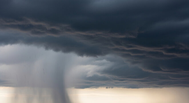 Dark, dramatic clouds with visible rain shafts, symbolizing change, power, and the approaching storm, representing nature's raw energy