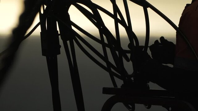 Worker silhouette industry professional operating equipment controls against hazy sunset background during evening shift.