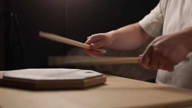Close-up of hands practicing drumming on a practice pad with drumsticks