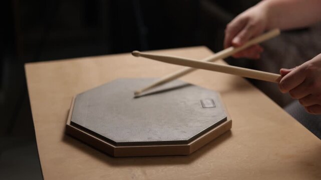 Close-up of hands practicing drumming on a practice pad with sticks