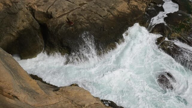 turquoise wave swirls between limestone rock ledges cliffside water motion valletta coast natural pattern malta coastline mediterranean sea sea spray foaming surf tidal surge wave action
