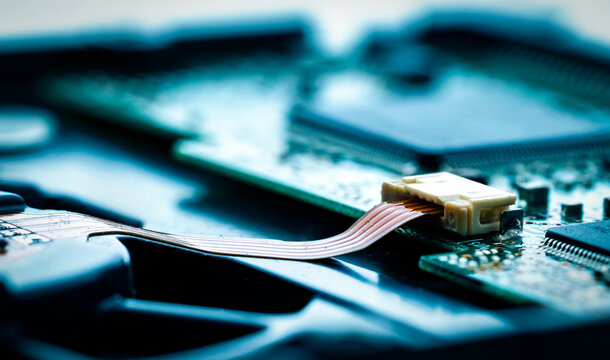 Macro close up of electronic circuit board with ribbon cable connector and integrated microchips. Semiconductor technology, embedded systems, artificial intelligence hardware and digital communication