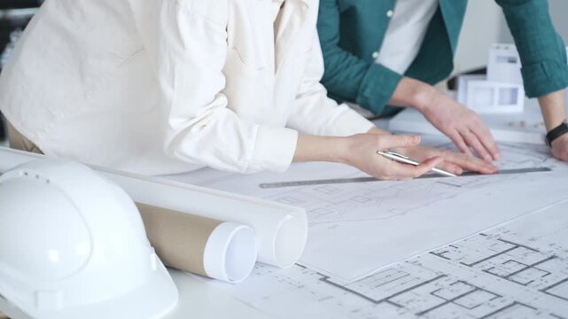 Architects discussing apartment building blueprint at office desk, using drafting tools for new architectural project design. Architecture and business concept
