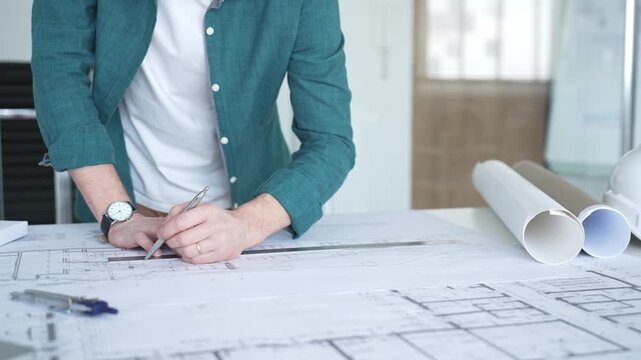 Architect designing building plan using ruler and pen, working on blueprints for construction and engineering project. Architecture and business concept