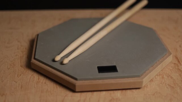 Drum practice pad with sticks on a wooden surface for quiet musical training