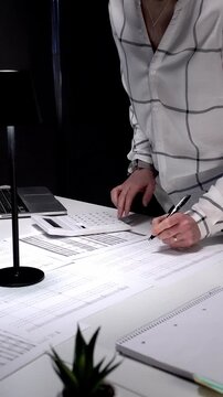 Financial specialist working late crunching numbers and analyzing data, completing important paperwork, calculating taxes, and managing audit preparation in a busy office environment