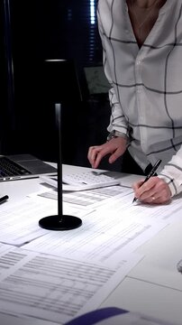 Financial specialist working late crunching numbers and analyzing data, completing important paperwork, calculating taxes, and managing audit preparation in a busy office environment