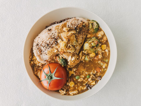 Nutritious chicken breast served with mixed vegetables, black rice, and a fresh tomato.
