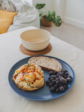 Nutritious homemade meal with savory salad, whole wheat bread, blueberries, and warm drink.