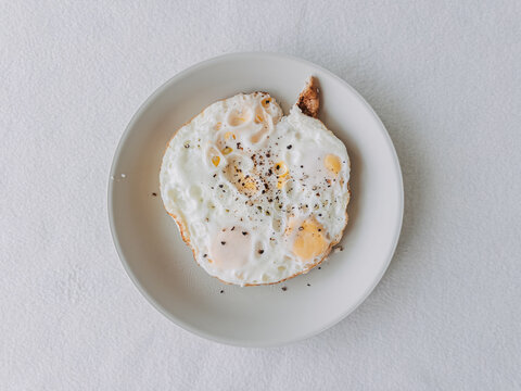 Delicious fried eggs with black pepper on a plate, ready for a healthy breakfast.