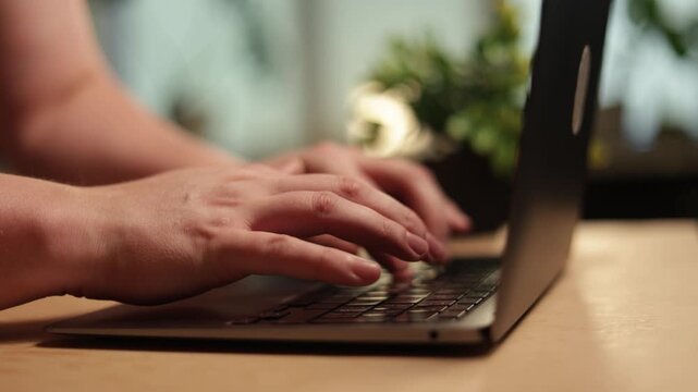 Close-up of hands typing on a laptop keyboard, working remotely or studying
